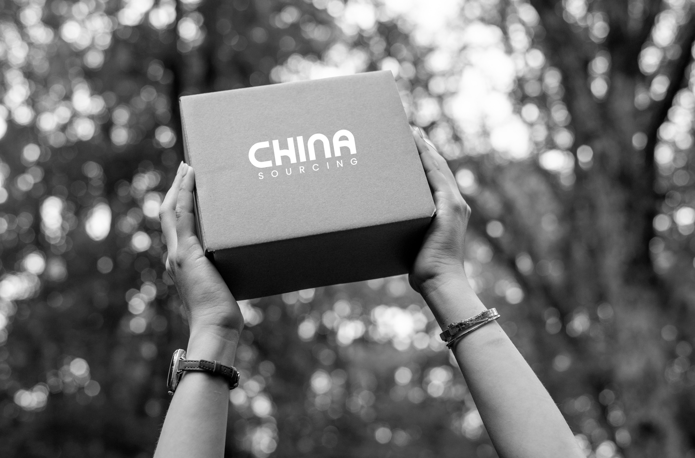 Hands lift a box with the words “China Sourcing,” reflecting niche China furniture sourcing.